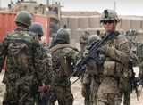 Associated Press fileAfghan soldiers (left) walk past a U.S. Army soldier outside a military base in Panjwai, Afghanistan. The agreement must be signed by the Afghan and U.S. presidents.